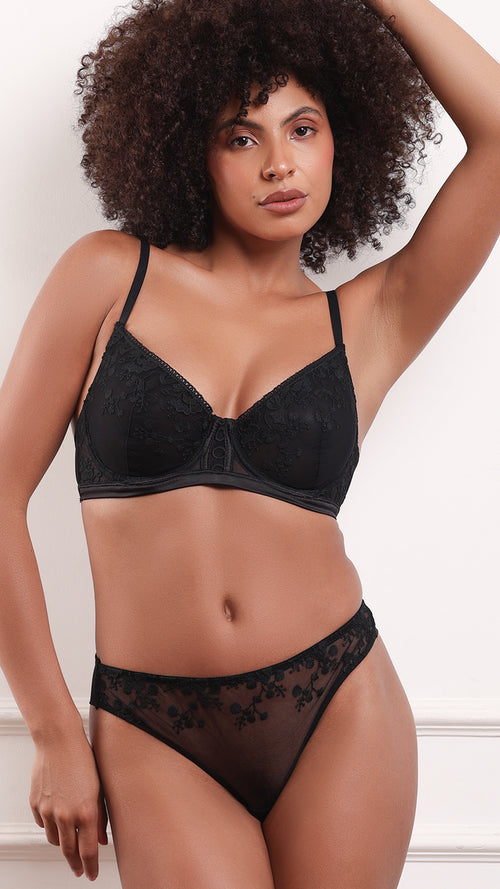 Woman wearing black sheer floral lace bra and matching briefs, front view