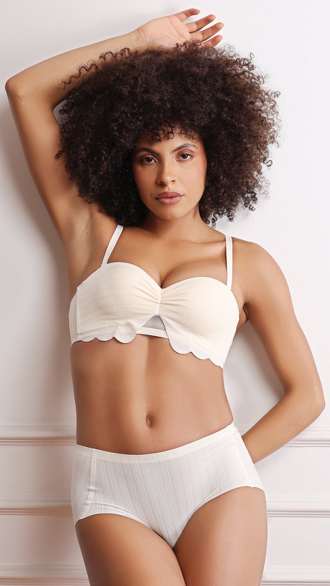 Model in ivory bandeau bra and briefs, arm raised front view.
