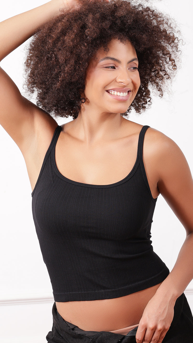 Black ribbed cami top worn with black pants, arms raised