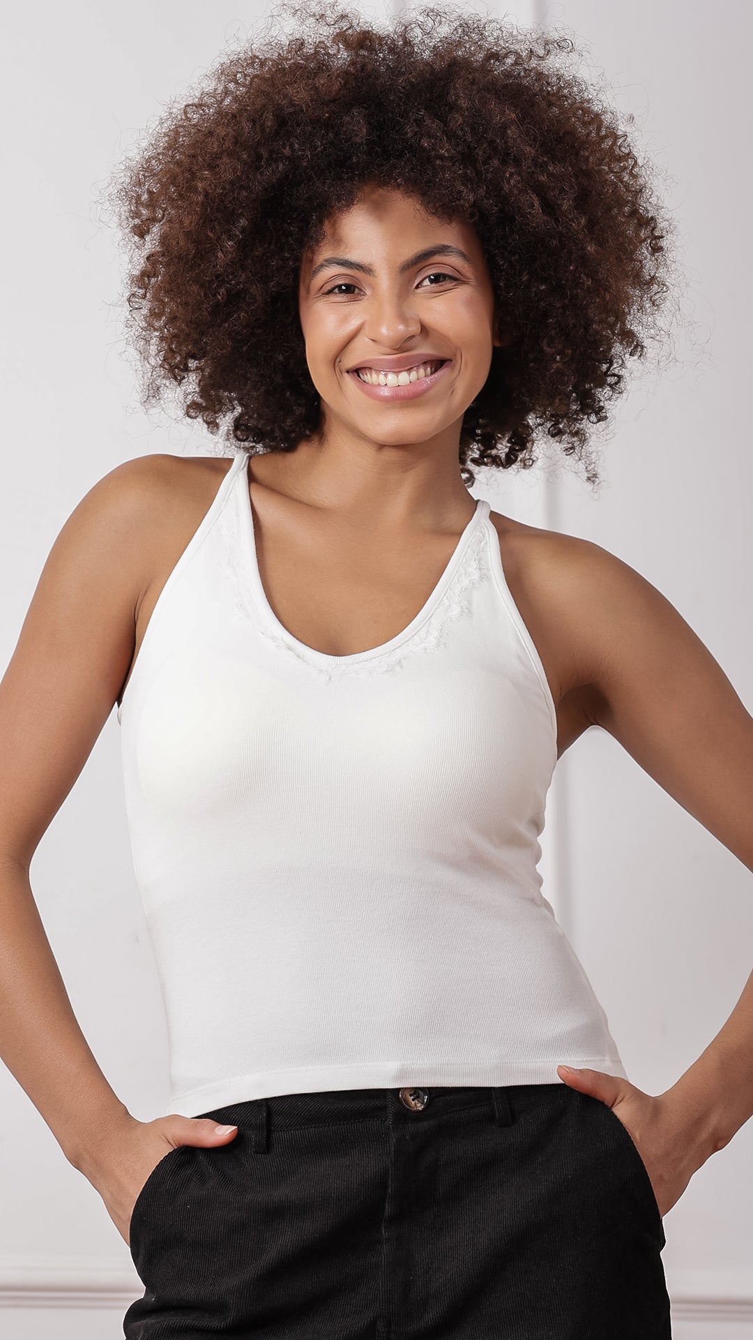 White lace-trim racerback tank top worn with black pants, front view