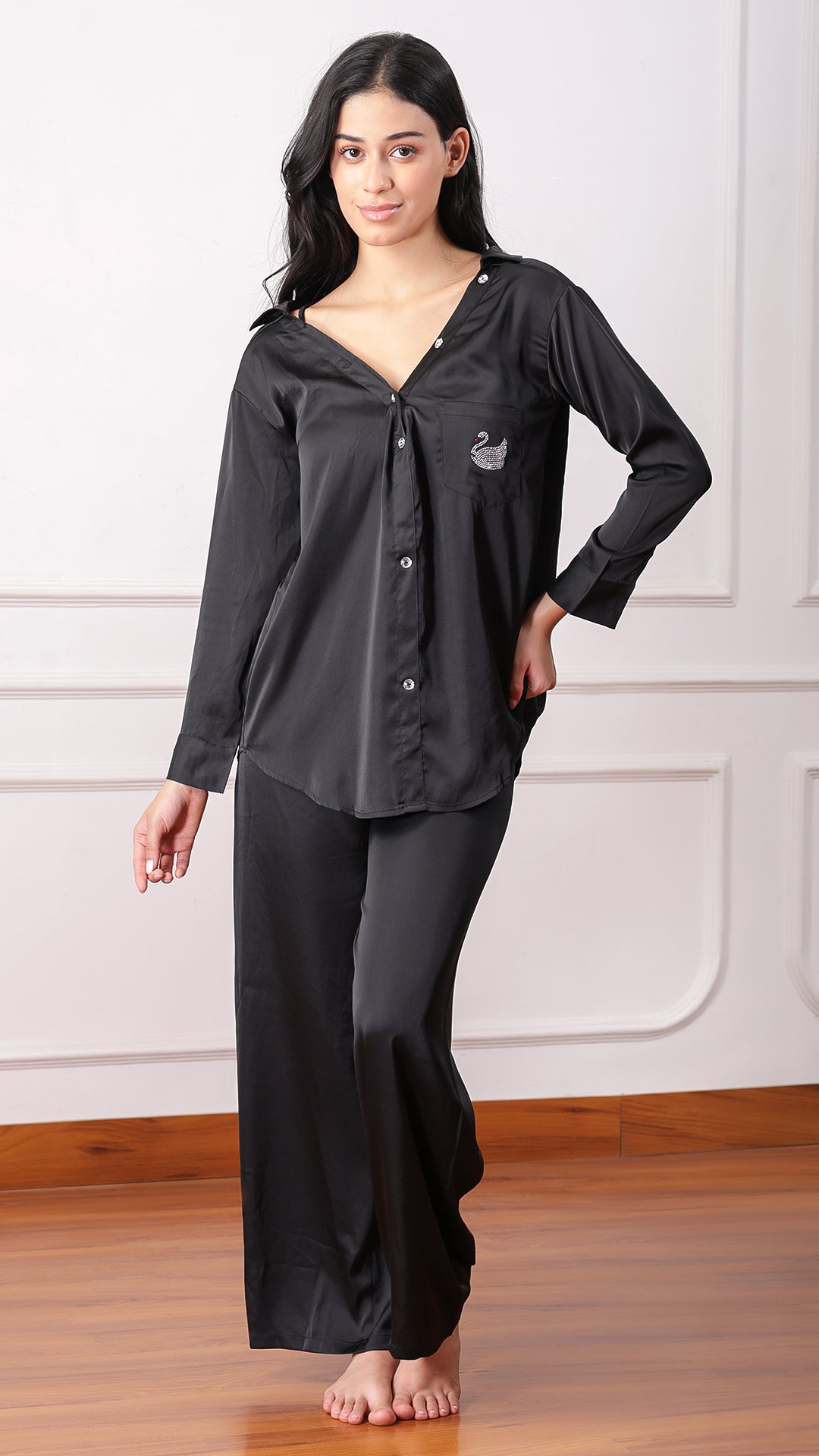 Woman wearing black satin pyjama set with swan embellished pocket