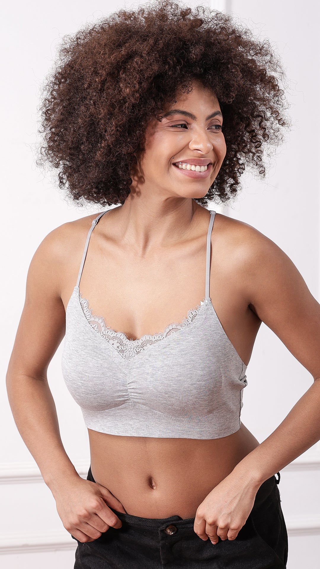 Model posing in grey lace-trim bralette, front view
