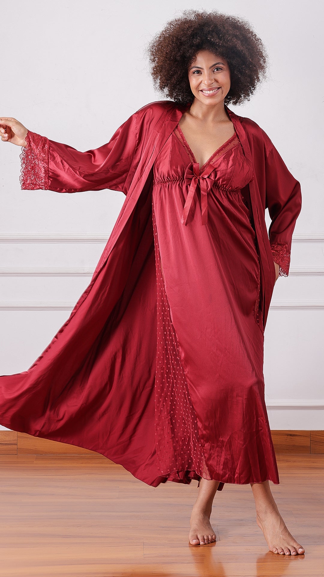 Woman wearing a maroon satin nightgown with matching robe, twirling