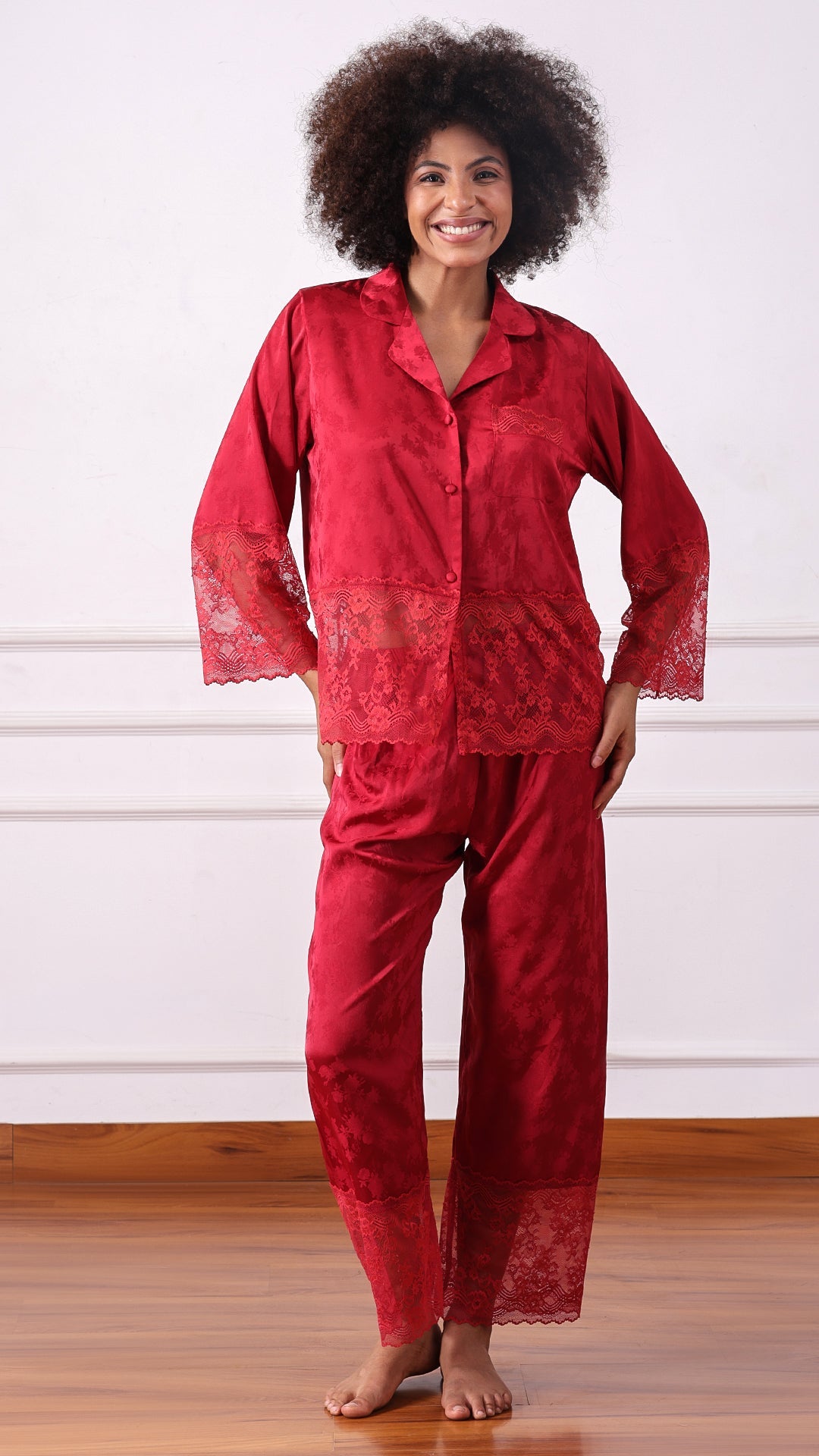 Woman wearing a red satin jacquard pyjama set with lace hem, full length