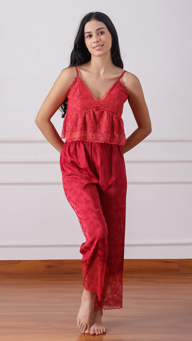 Woman wearing a red lace cami and satin pyjama pants, smiling