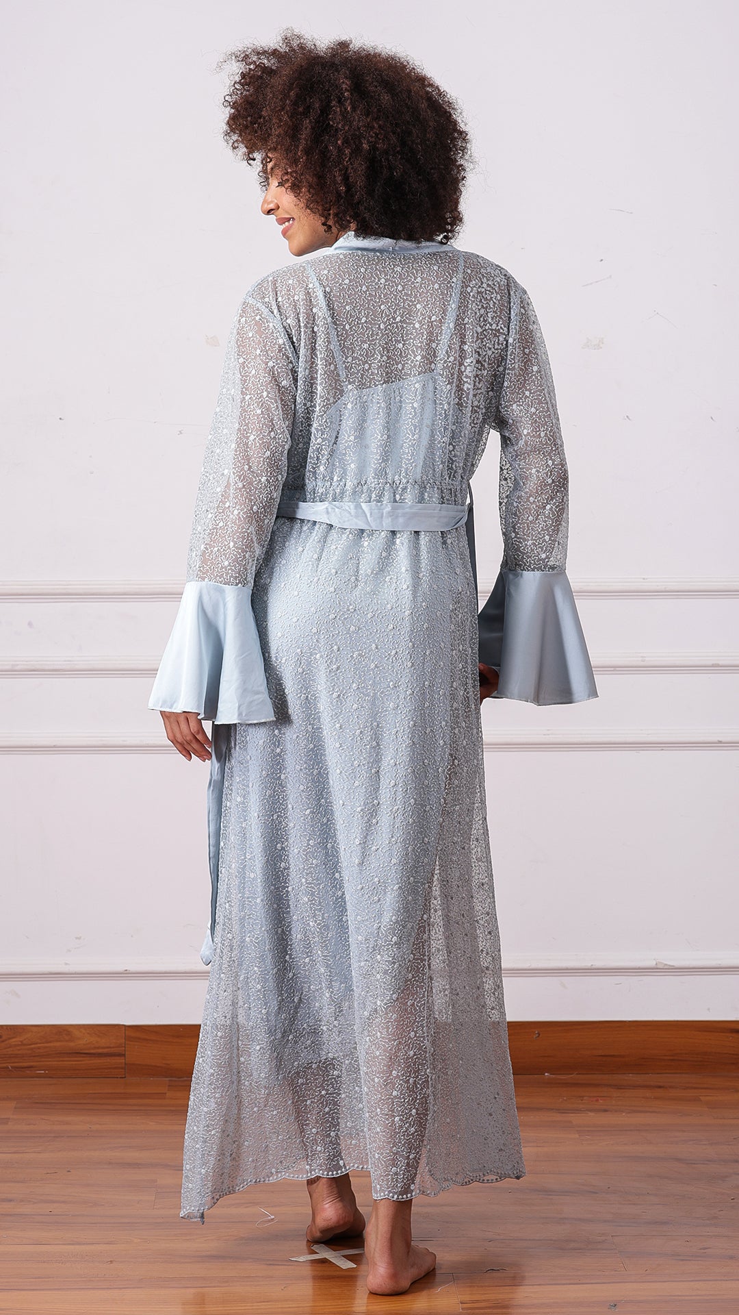 Back view of woman wearing pale blue sheer floral lace robe