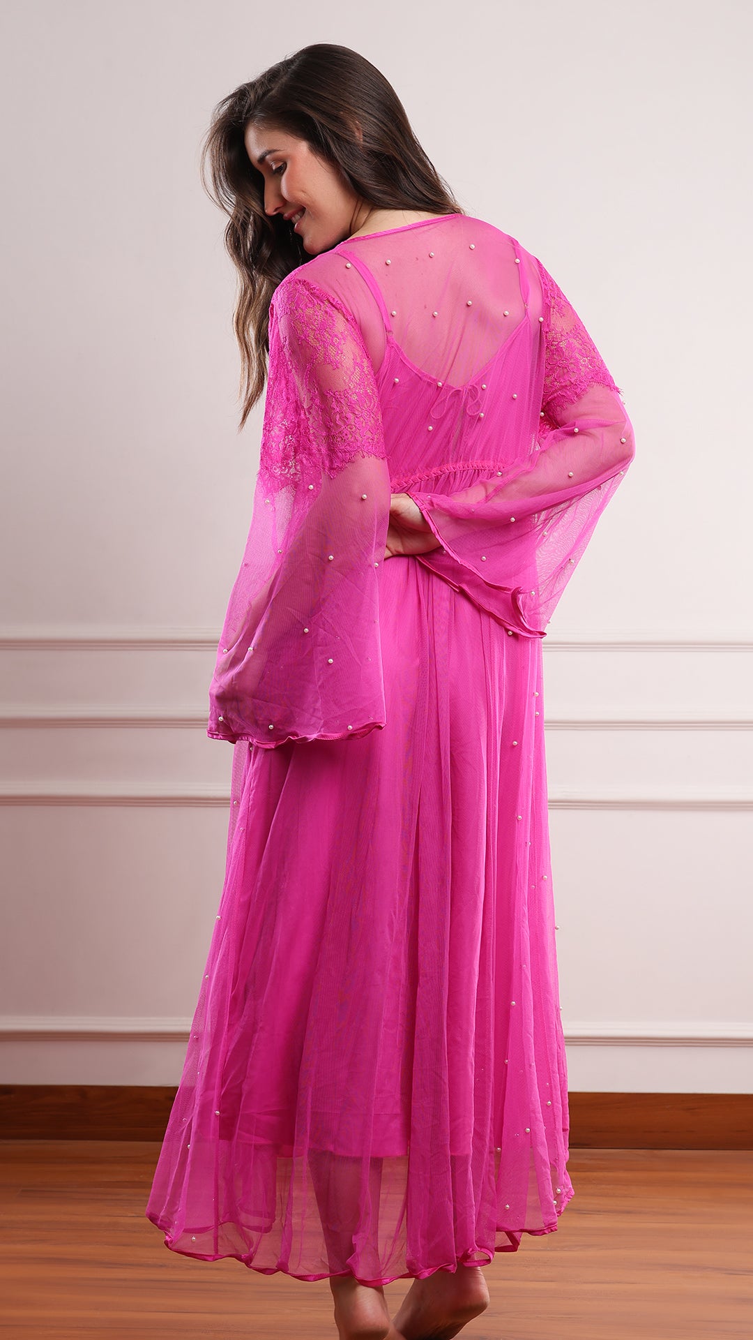 Back view of fuchsia pink pearl-beaded sheer robe showing lace shoulder detail, bell sleeves and high-low hem
