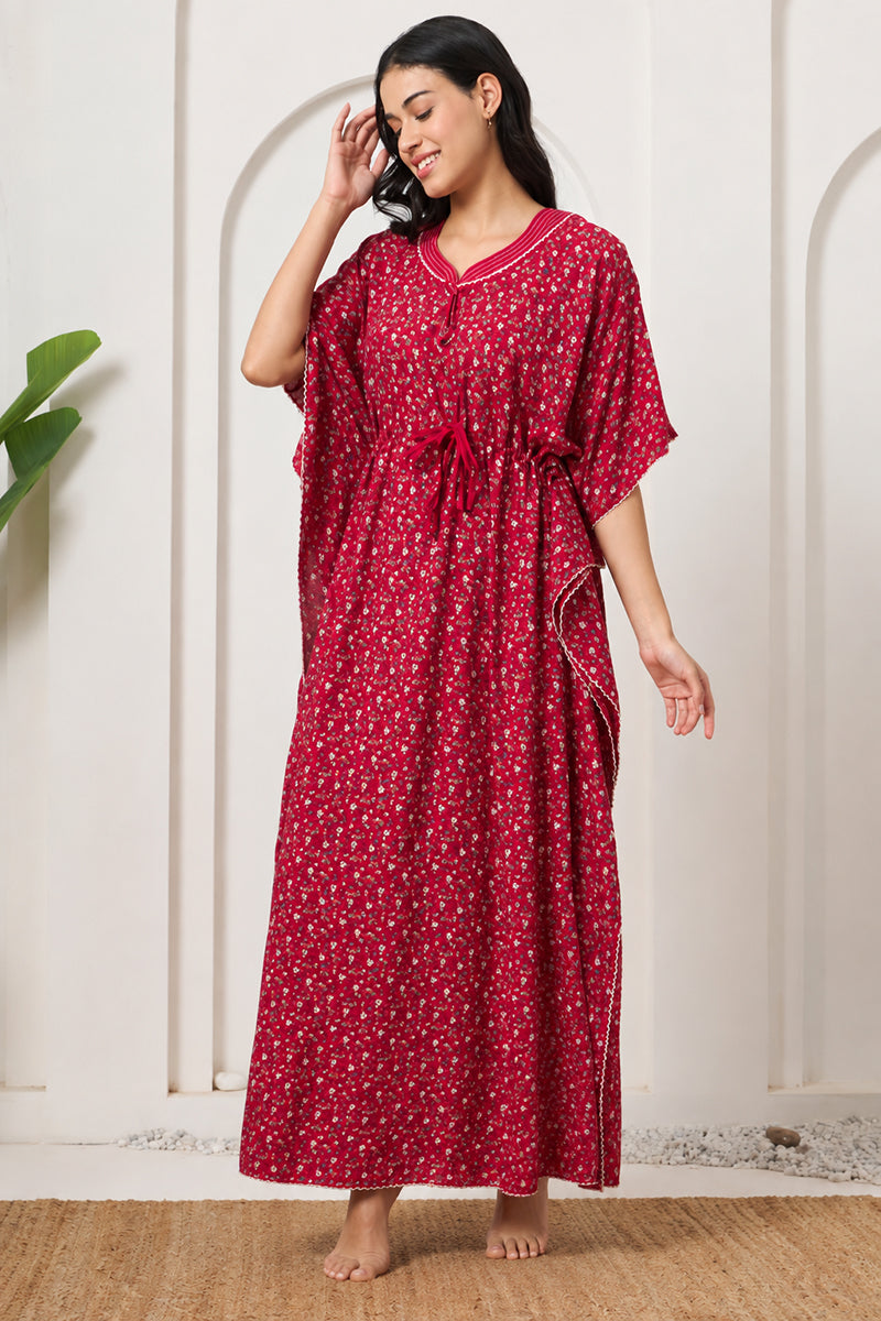 Woman standing with hand in hair, wearing a red floral print kaftan