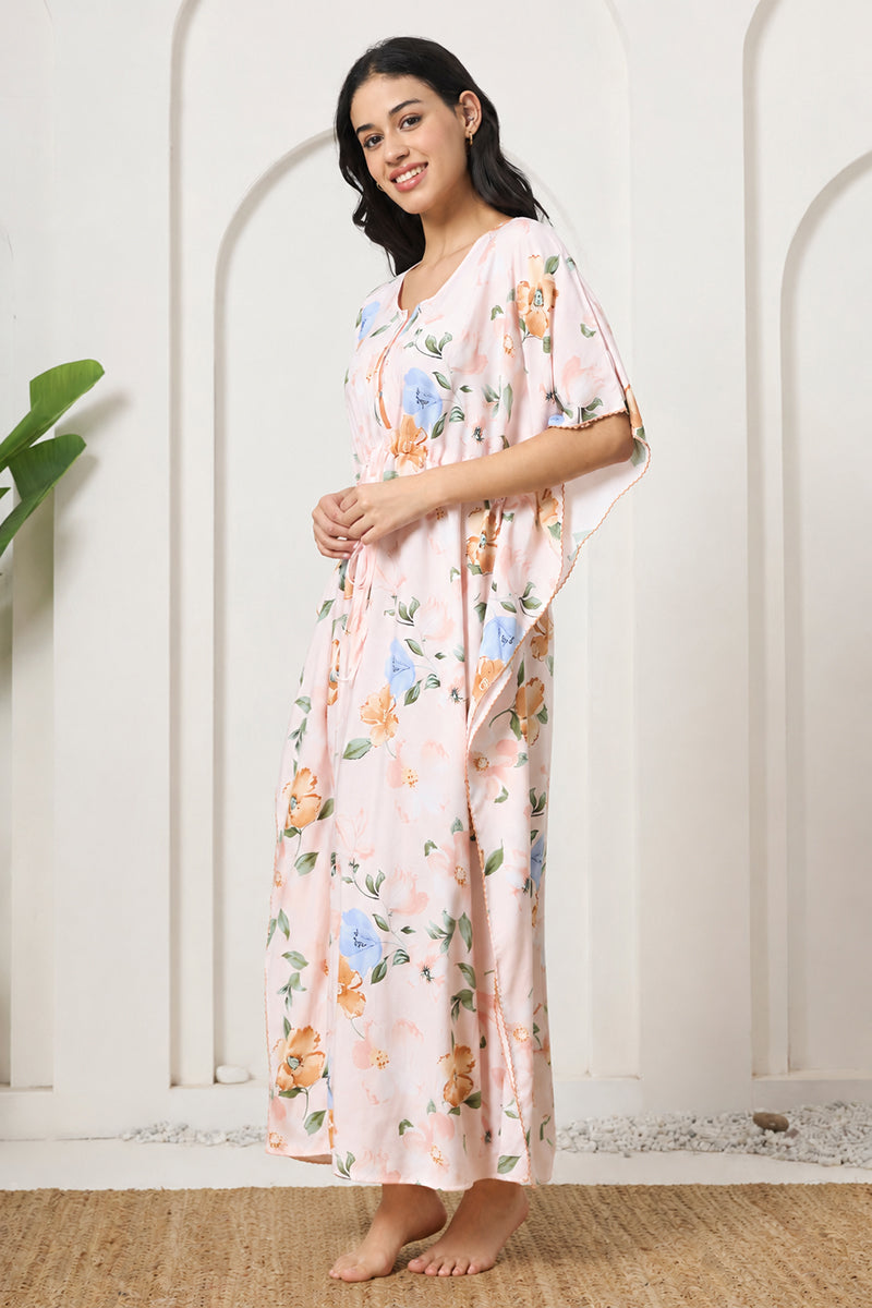 Woman standing sideways in a pink floral kaftan