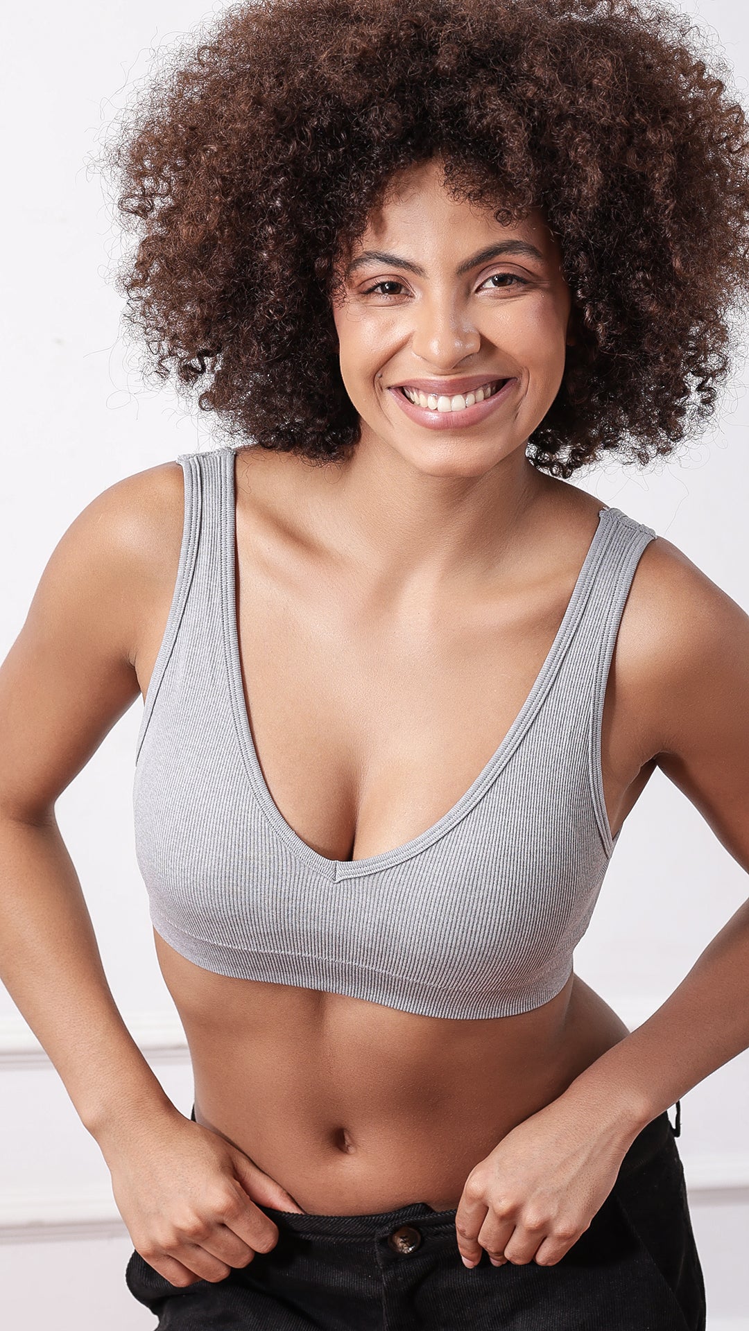 Side view of model wearing beige ribbed V-neck bra with arm raised