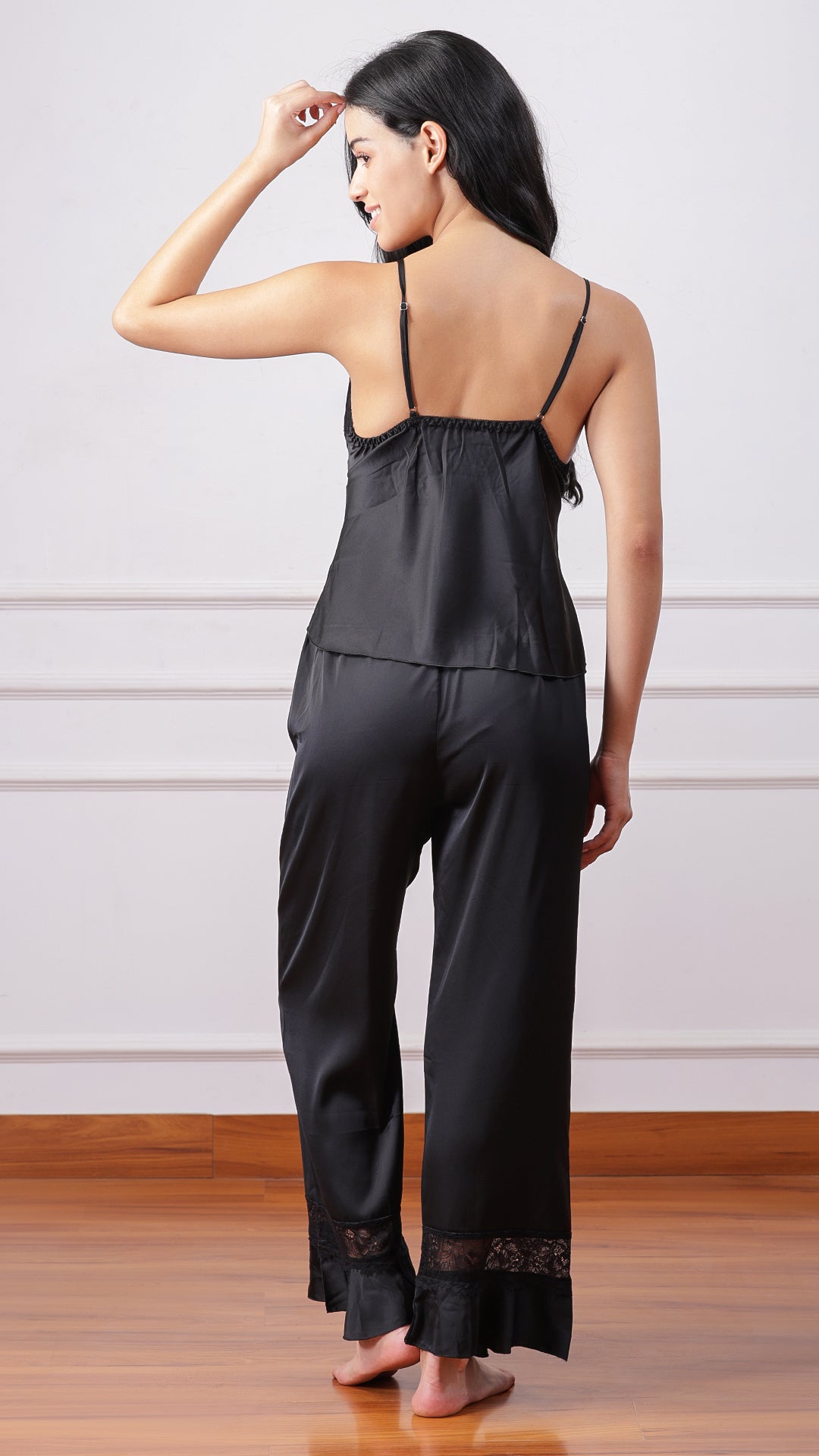 Back view of woman wearing black satin camisole and pyjama pants
