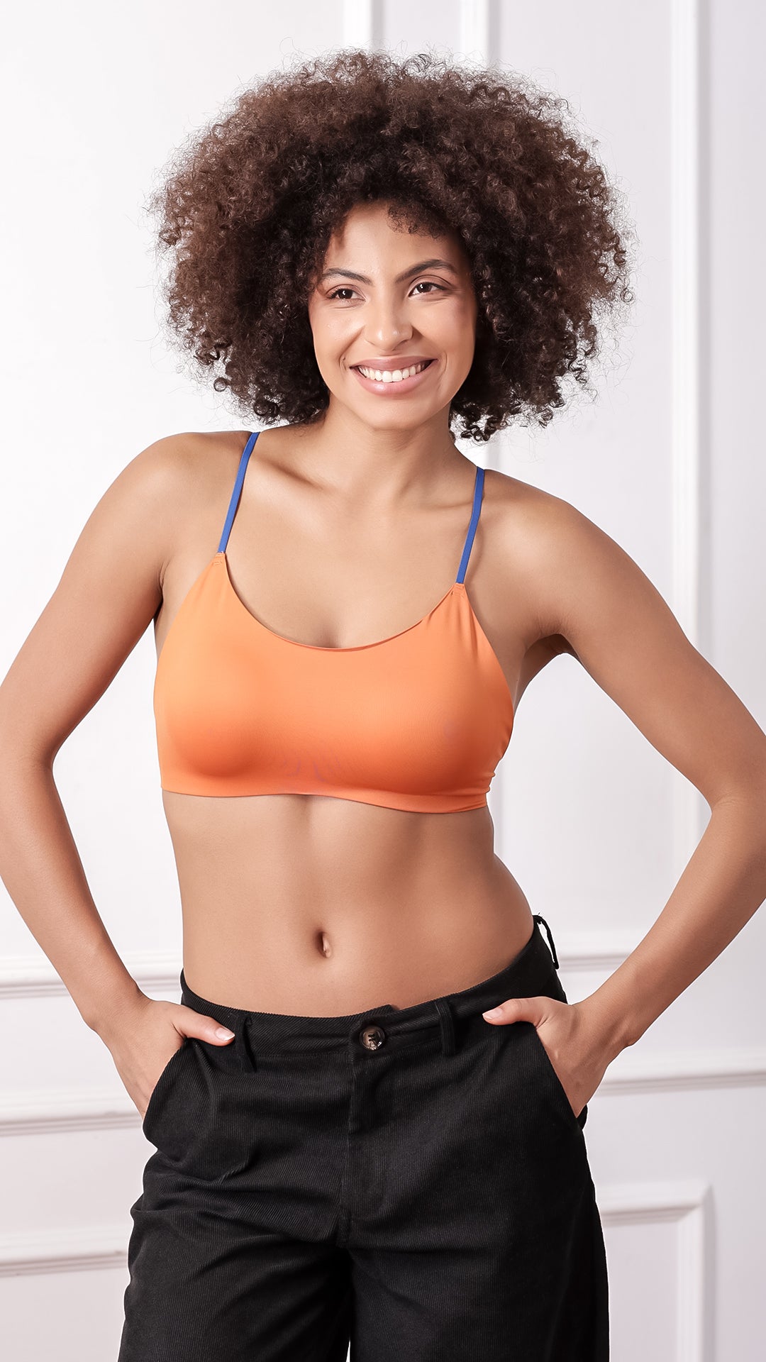 Model posing in orange bralette with contrast straps, front view