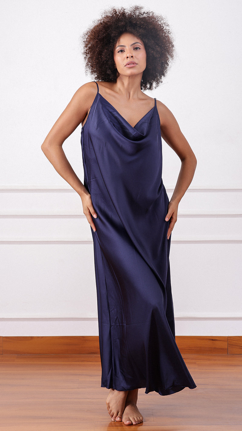 Woman wearing a navy satin cowl-neck slip dress, hands on hips