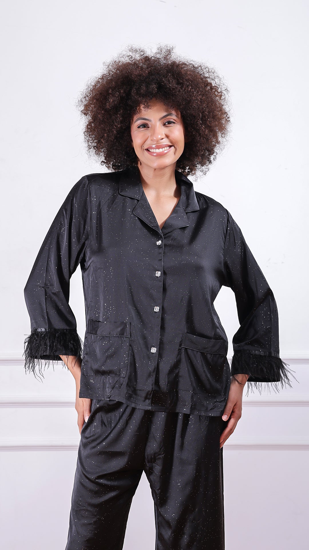 Woman posing in black glitter satin shirt and trouser pyjama set