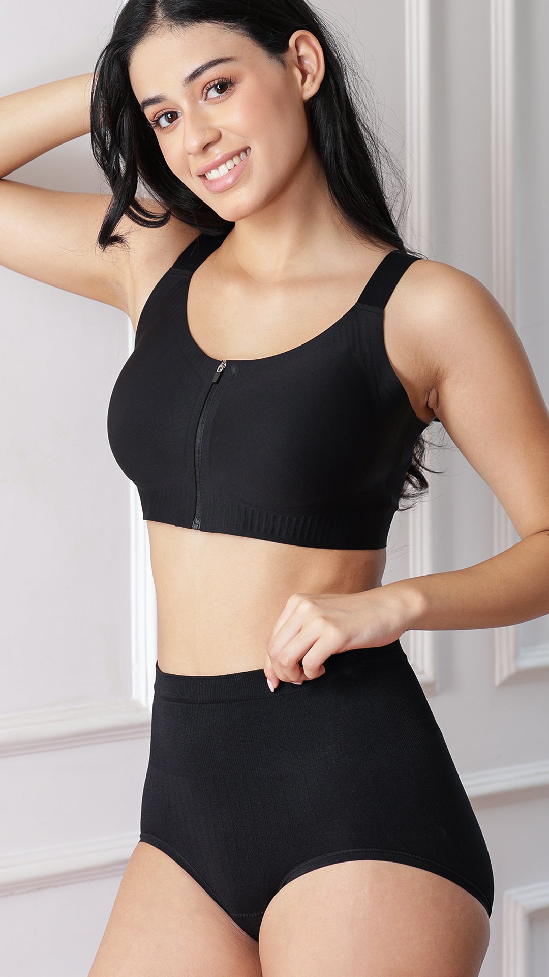 Model wearing black sports bra and high-waist shaper brief, side angled view