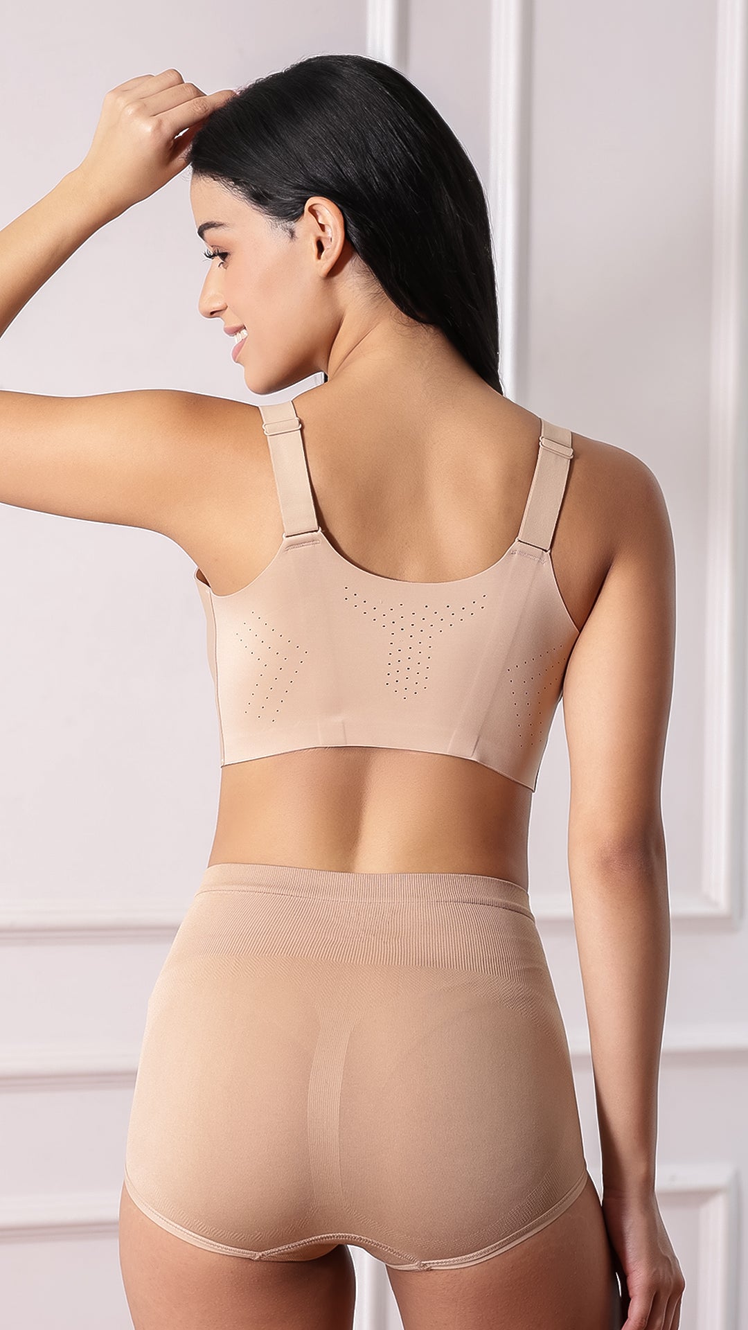 Back view of beige sports bra showing wide straps and perforated ventilation