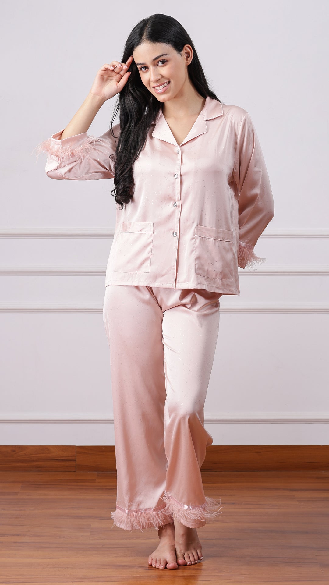 Woman standing in blush pink satin pyjama set, full-length front view
