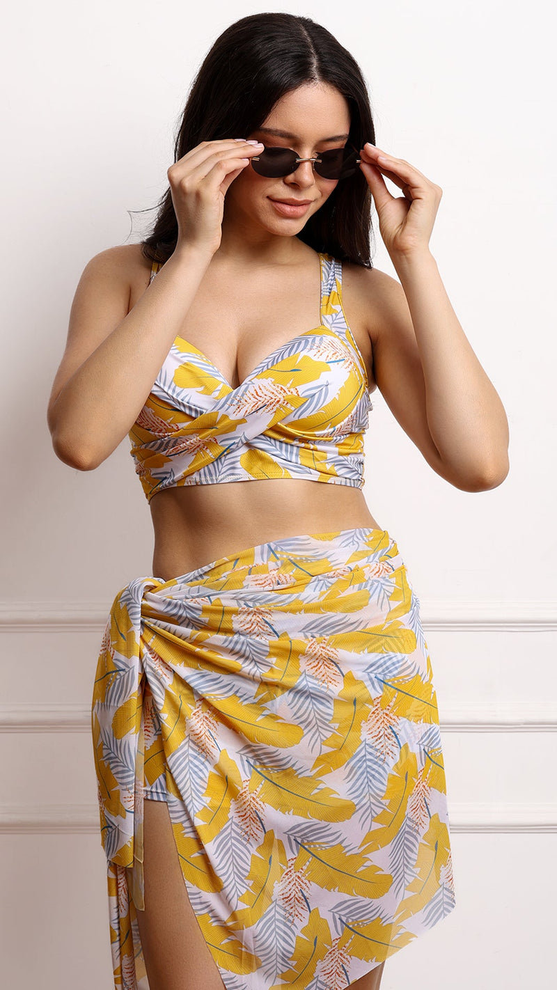 Woman adjusting sunglasses in tropical print swim set with sarong