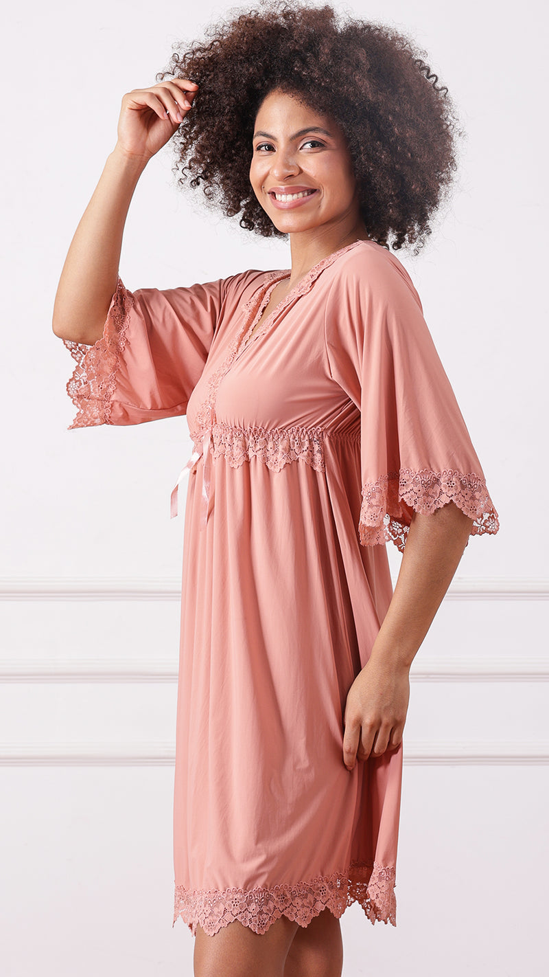 Side view of woman wearing a pink lace-trimmed nightdress, hand in hair