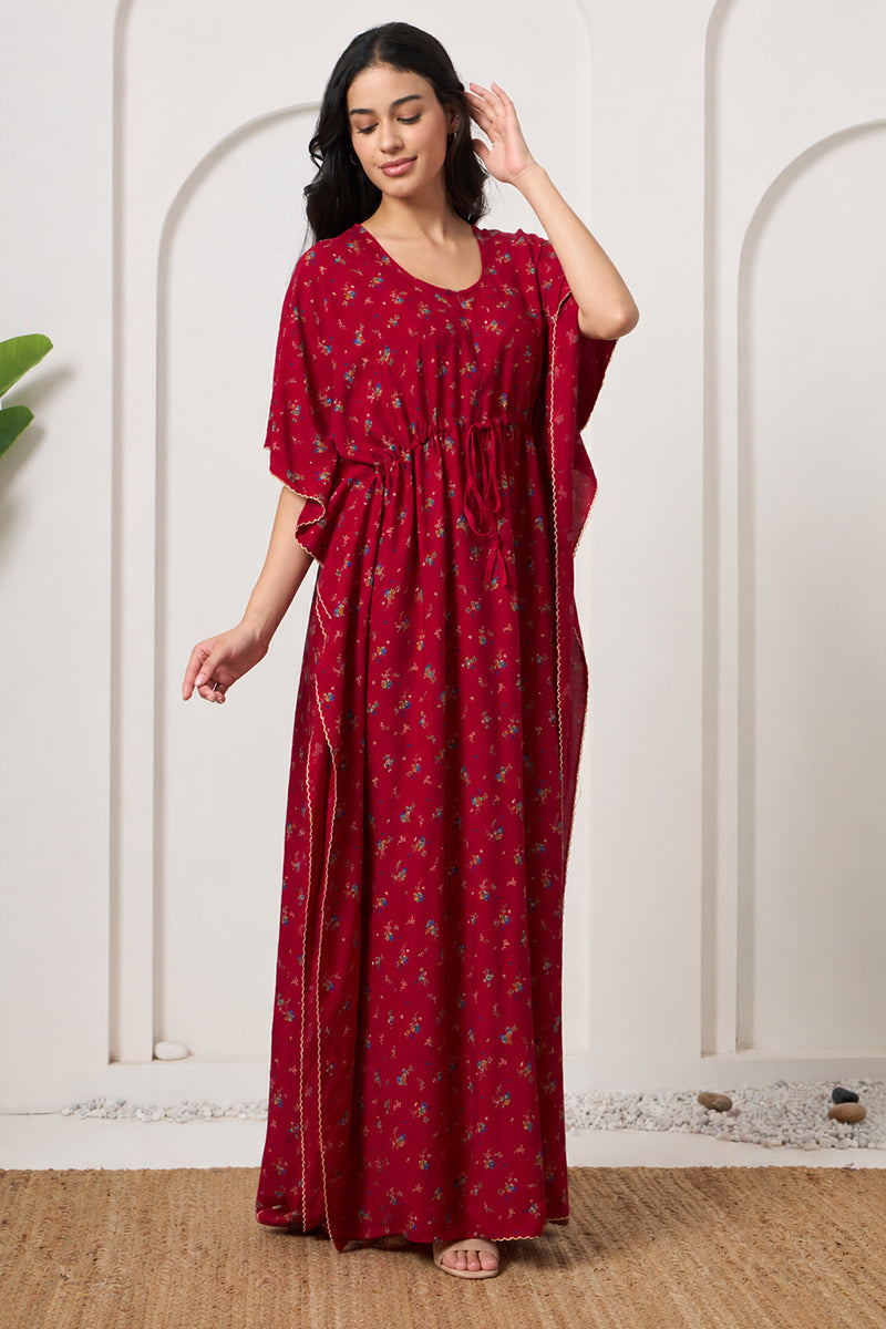 Woman smiling with hand in hair, wearing a red floral kaftan