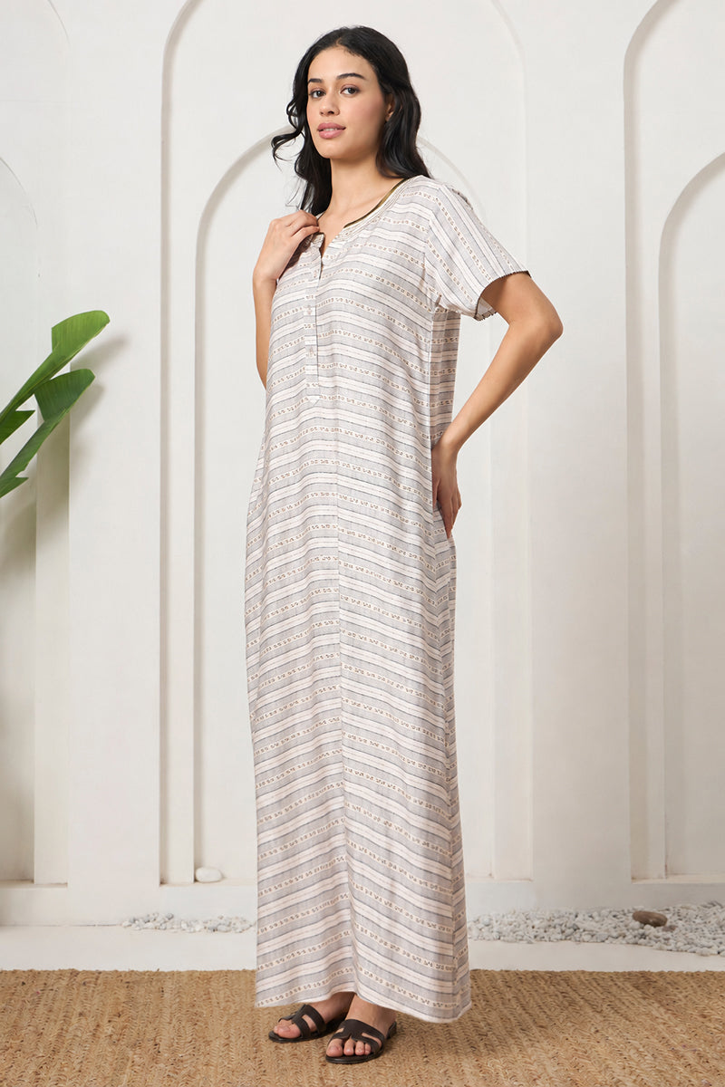 Woman posing sideways in a beige striped nightgown