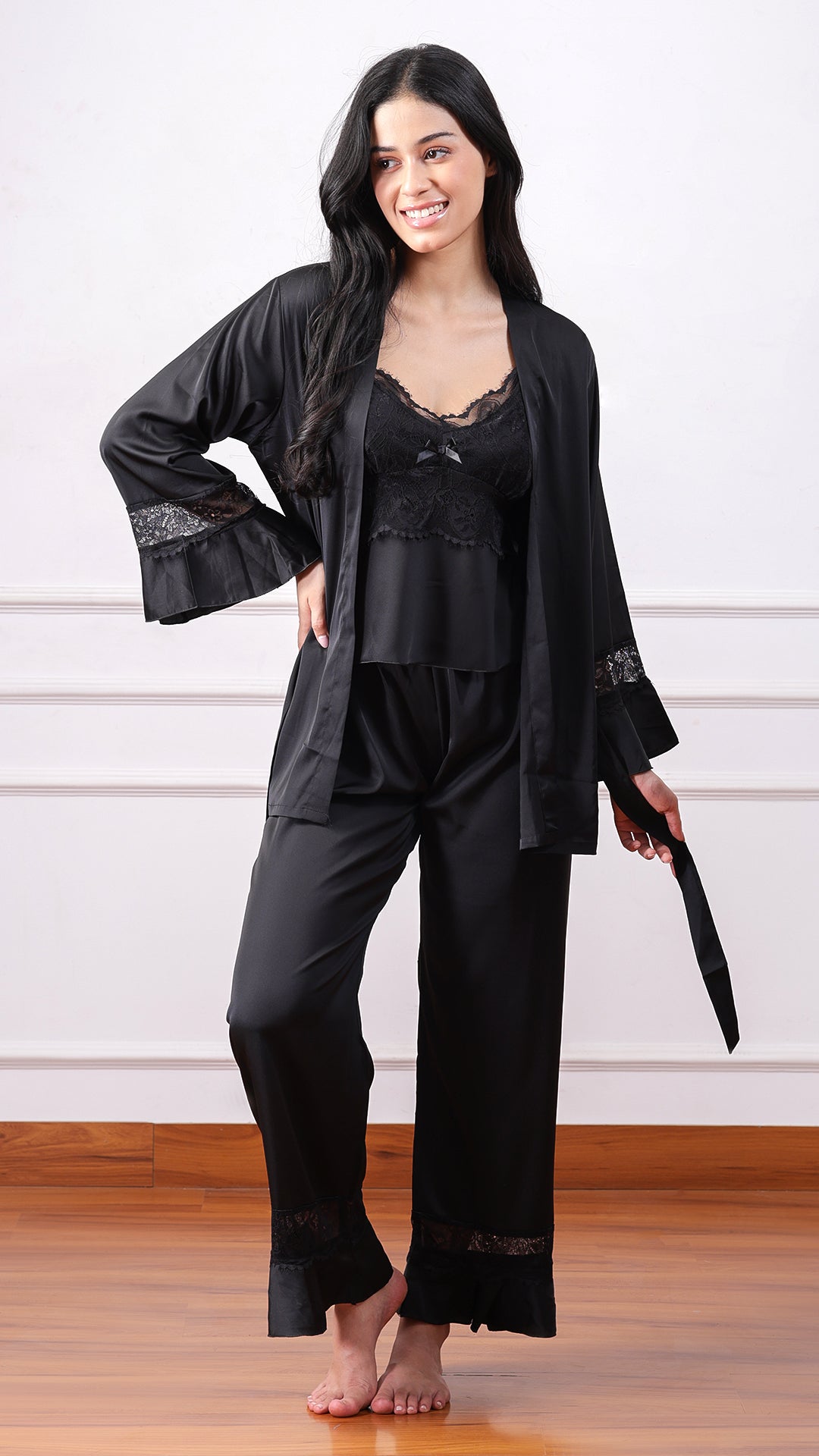 Woman wearing black satin robe with lace camisole and pants, front view