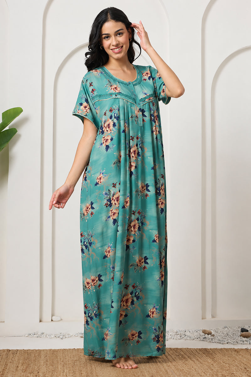 Woman standing with hand near hair, wearing a teal floral nightgown
