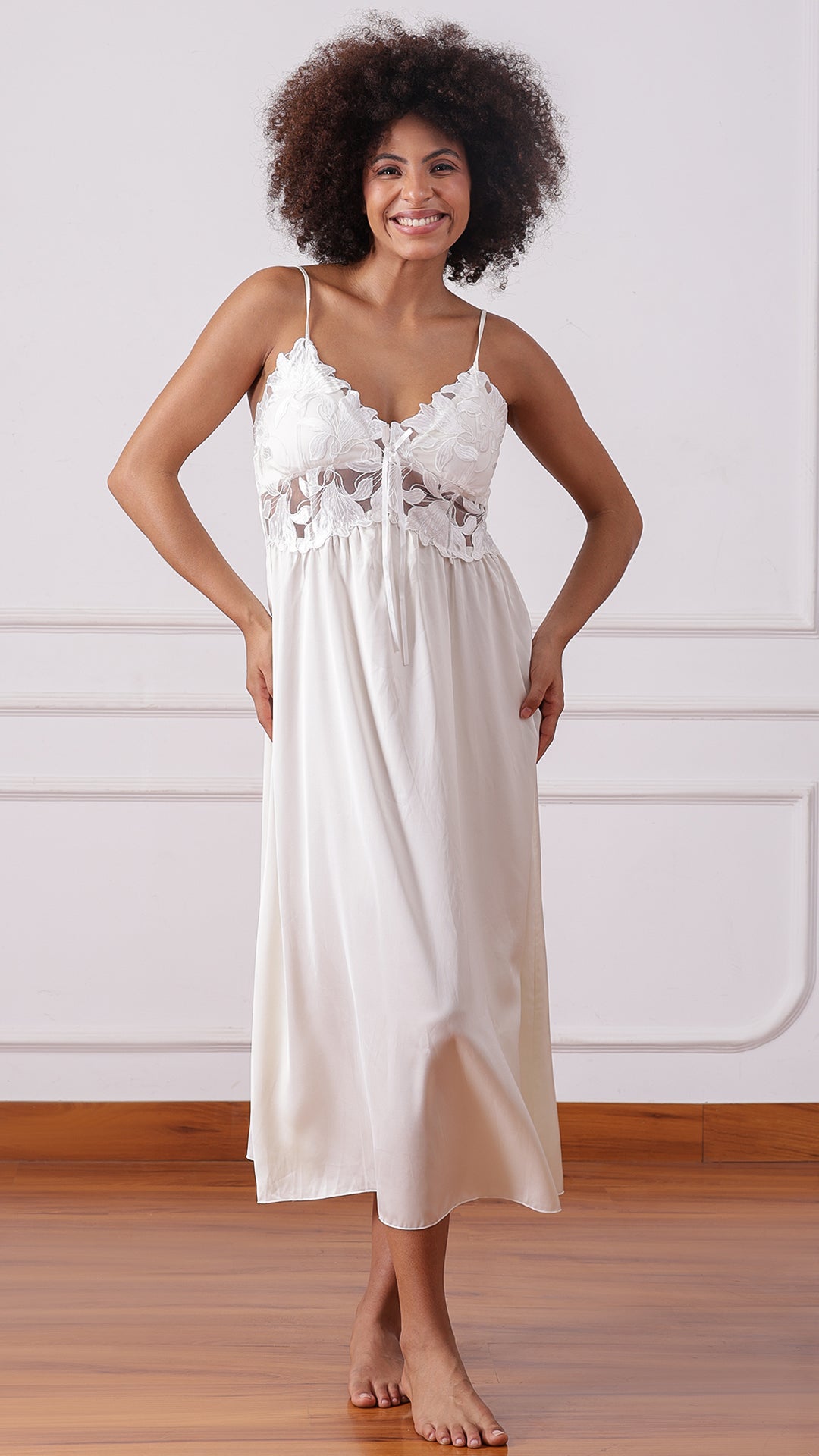 Woman wearing an ivory satin nightgown with floral lace bodice, hands on hips
