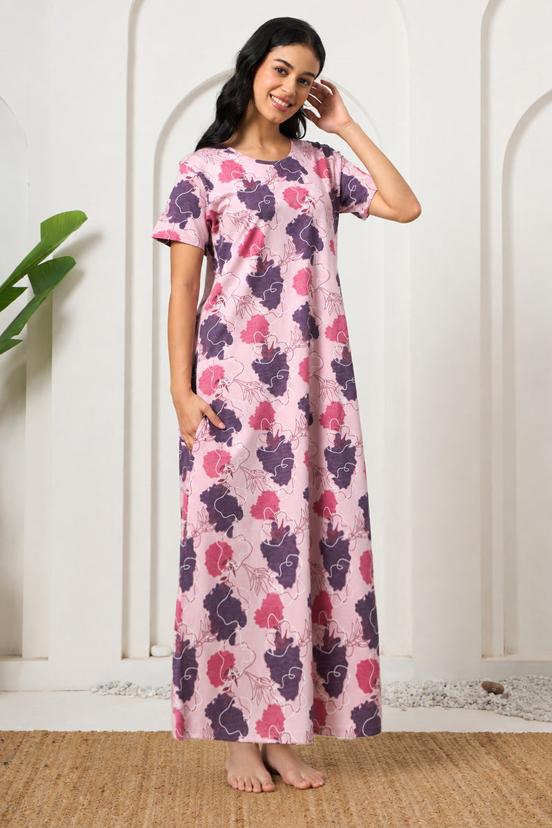 Woman smiling in a pink and purple floral print nightdress, hand in hair
