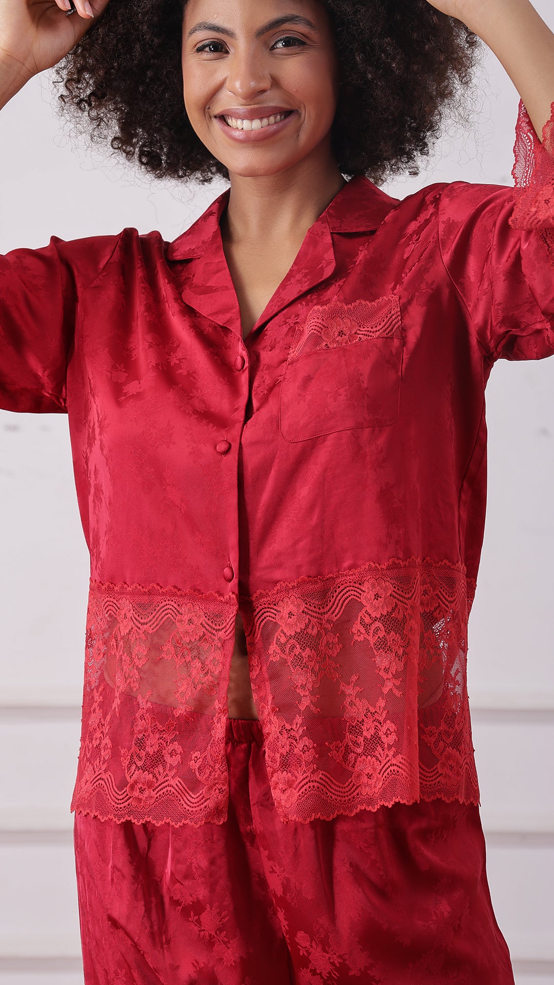 Close-up of woman wearing a red satin jacquard pyjama set with lace trim