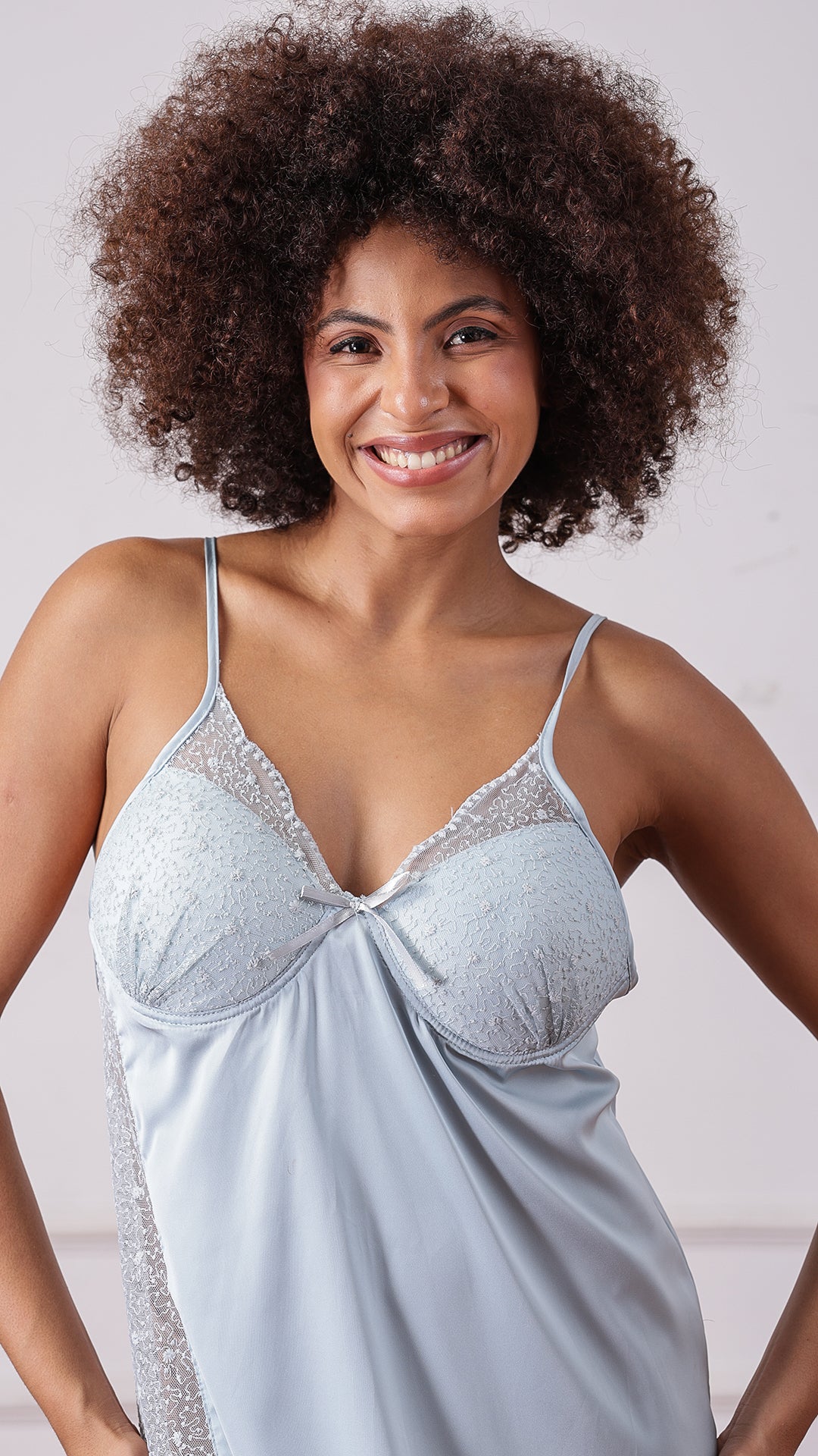 Close-up of woman smiling in pale blue satin lace-trim nightgown
