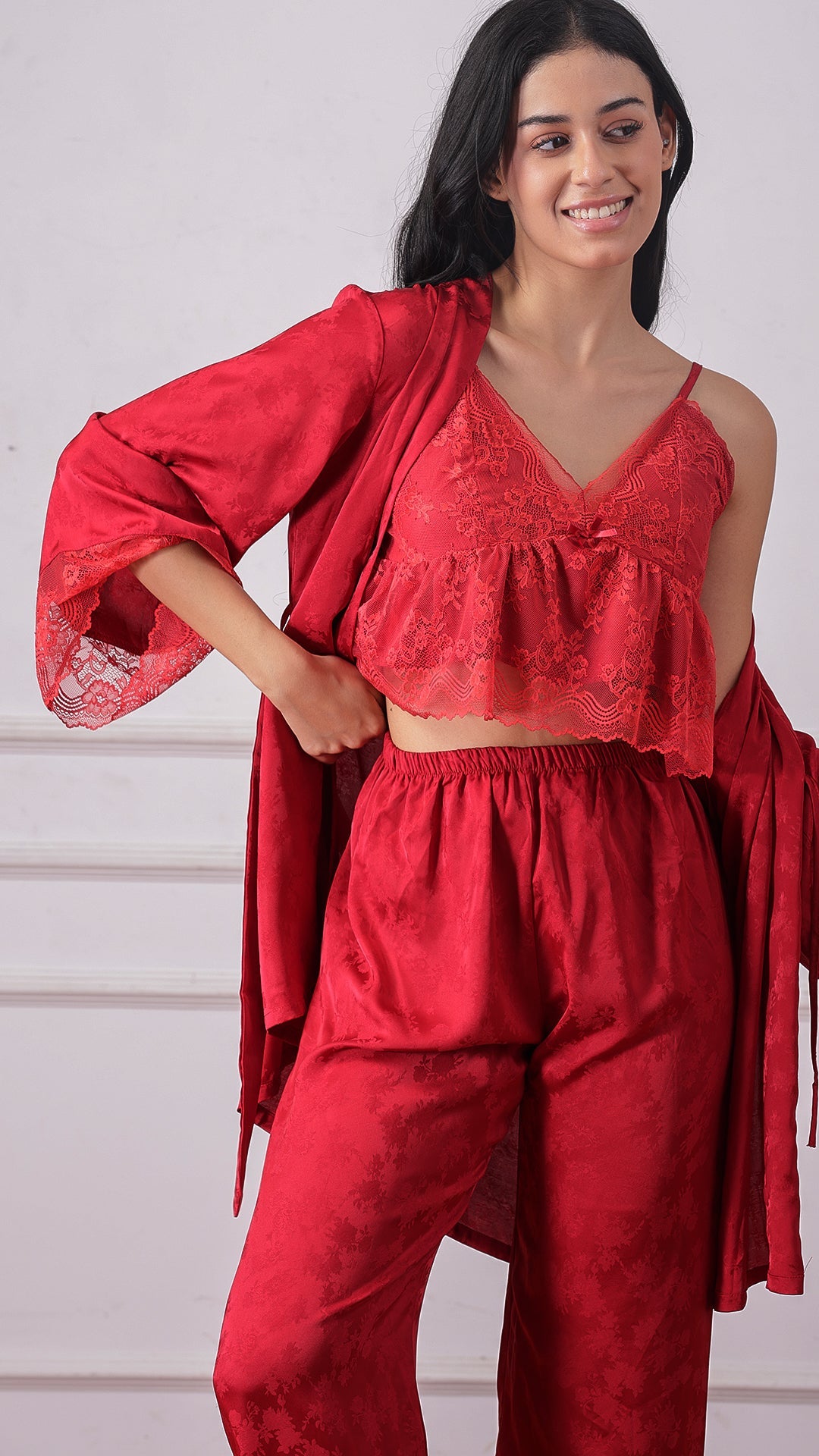 Woman wearing a red lace cami and satin pyjama set with matching robe