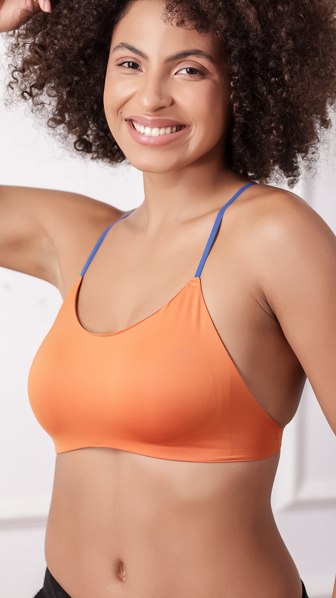Close-up of orange bralette scoop neckline and blue straps