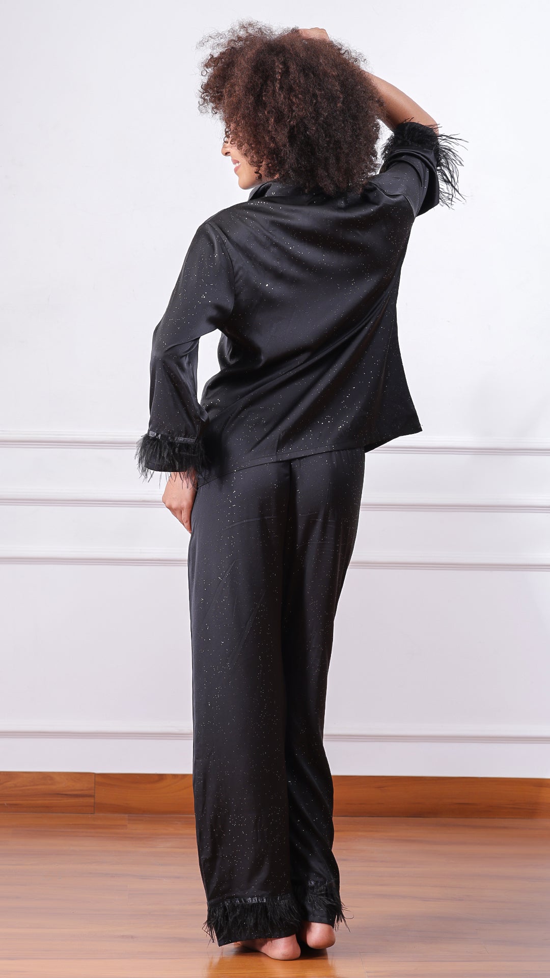 Back view of woman wearing black glitter satin pyjama set