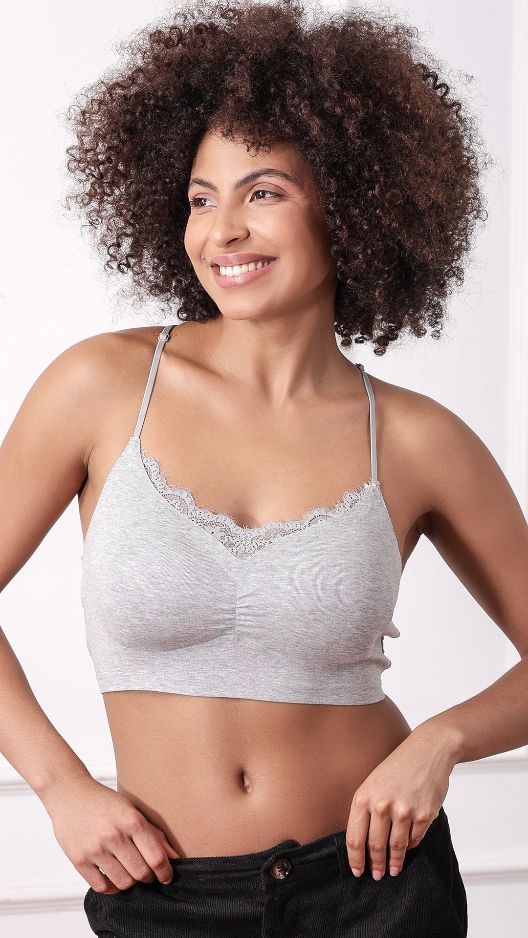 Woman wearing grey racerback bralette with lace trim, front view