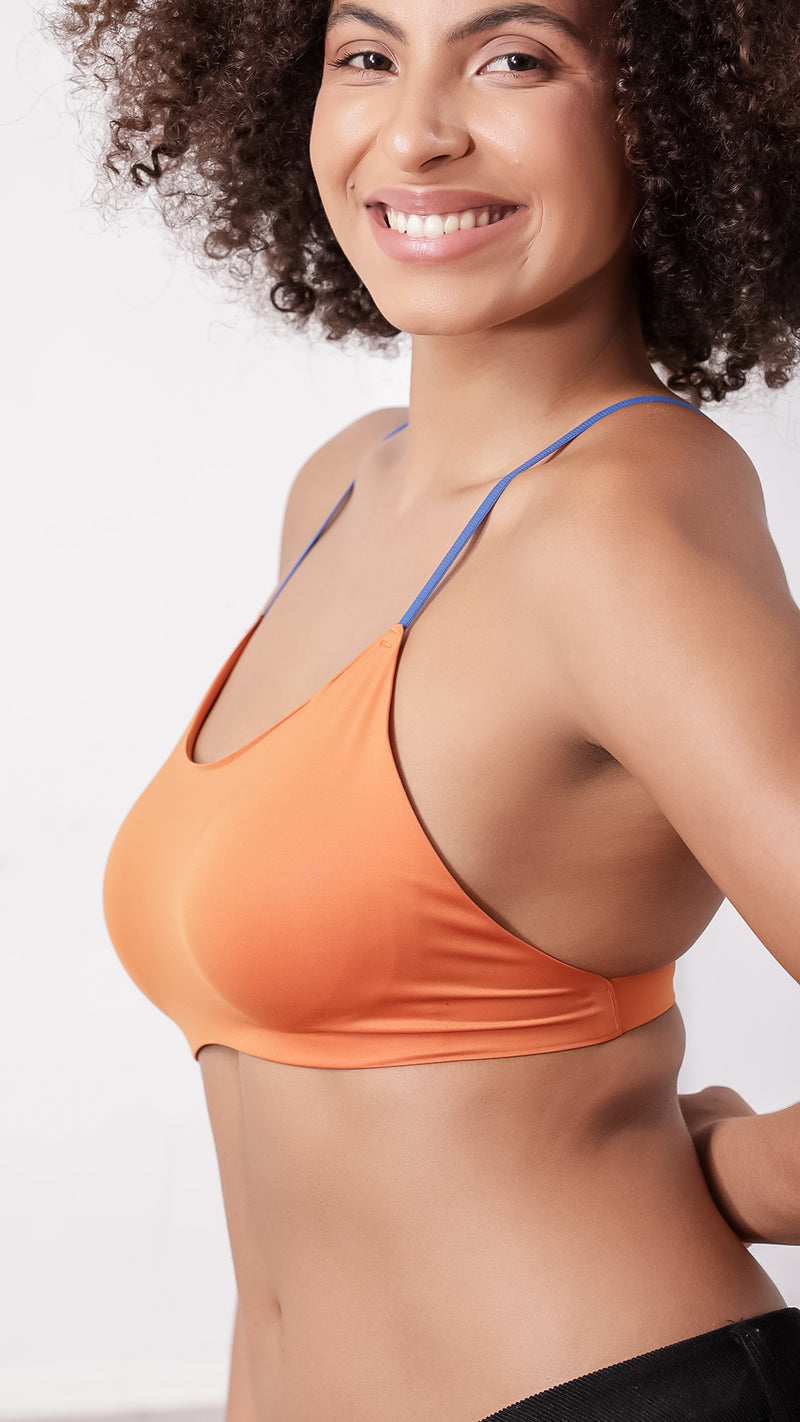 Side view of woman wearing orange bralette with blue straps