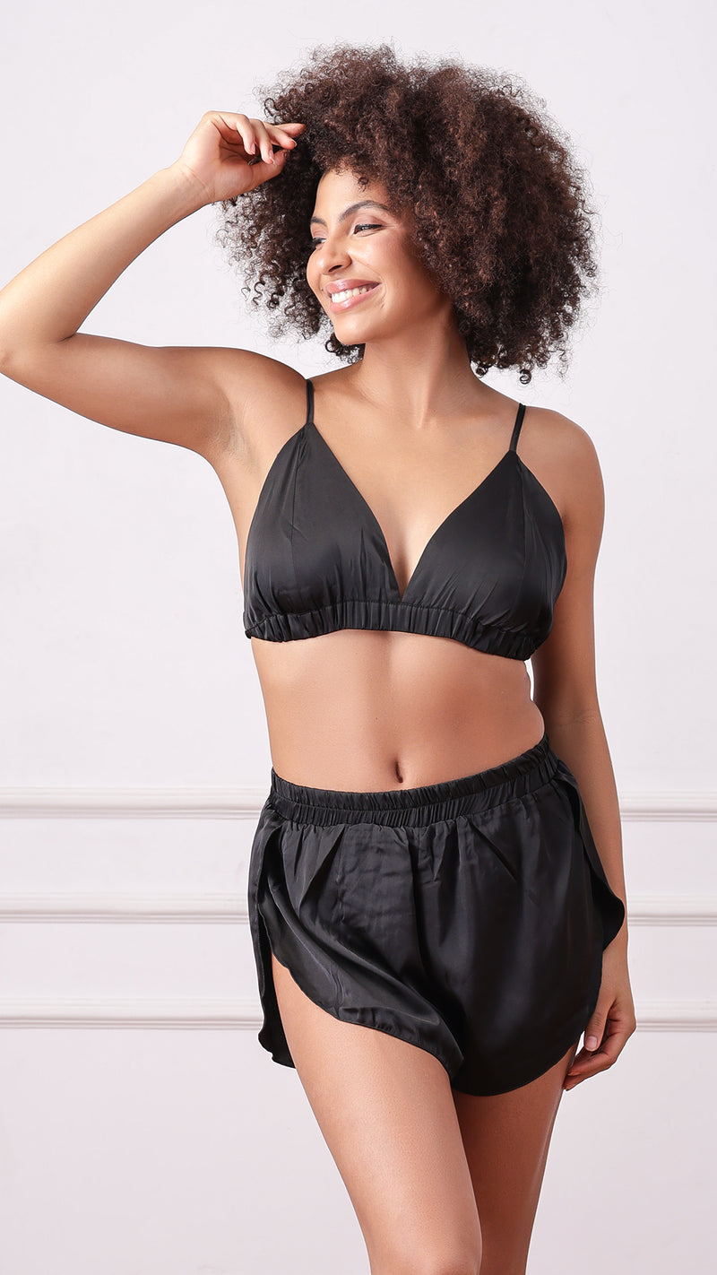 Woman posing in black satin bralette and shorts set