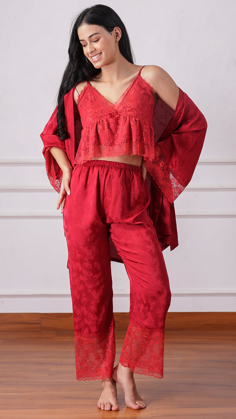 Woman wearing a red lace cami and satin pyjama pants, hand on hip