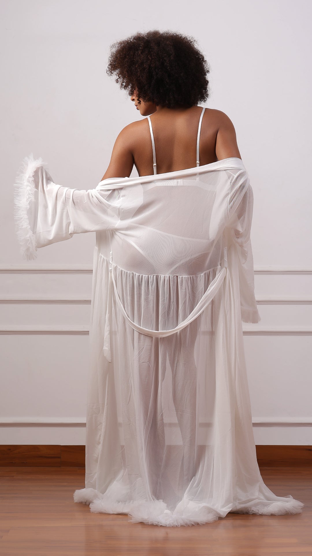 Back view of woman wearing white sheer ruffle-cuff robe