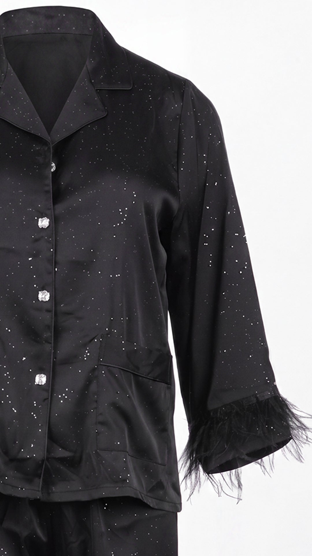 Close-up product shot of black satin shirt feather cuff and pocket detail