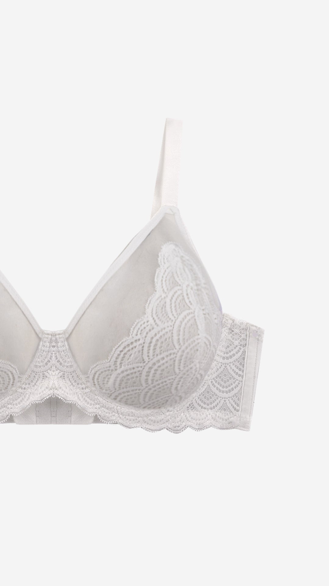 Close-up of white lace demi bra strap and scalloped cup edge on white background