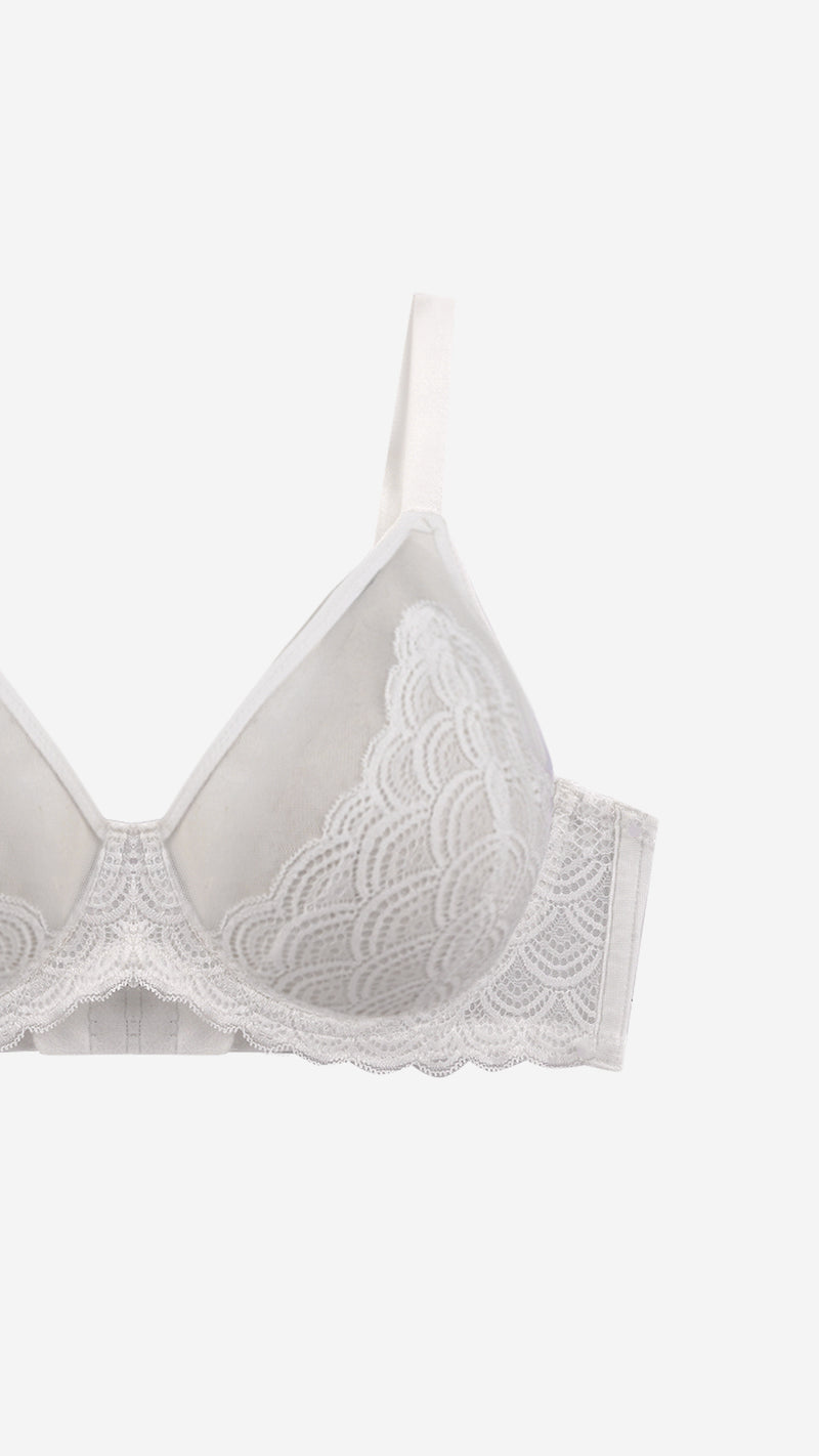 Close-up of white lace demi bra strap and scalloped cup edge on white background