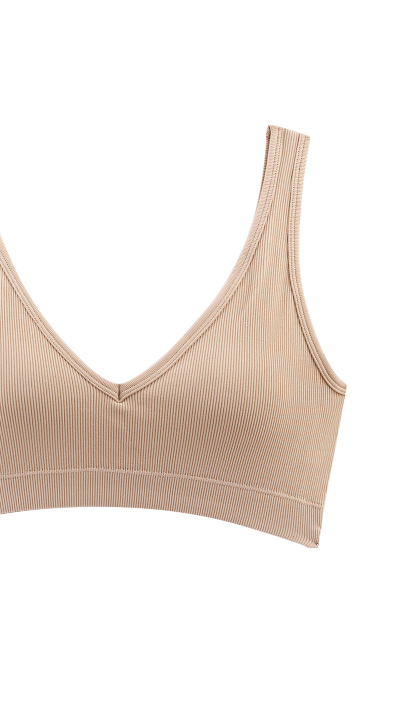 Close-up of beige ribbed bra strap and V-neck edge on white background