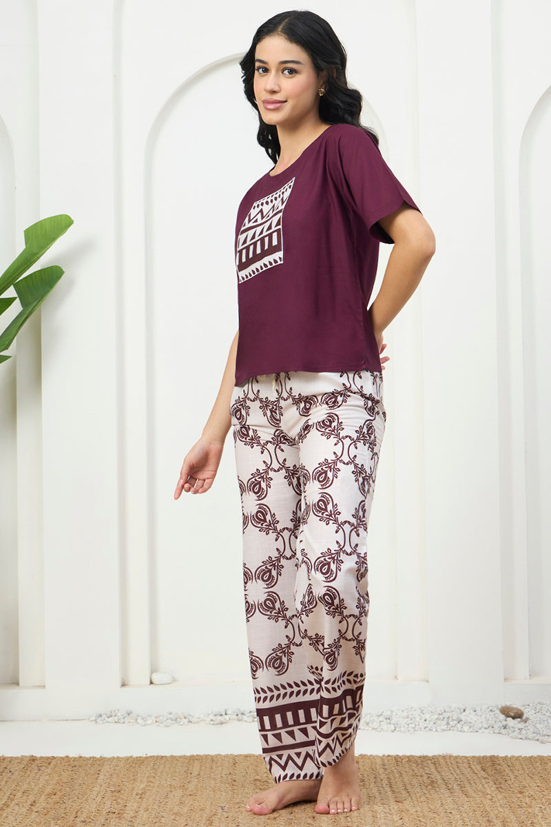 Woman standing in a wine graphic top and floral print pants