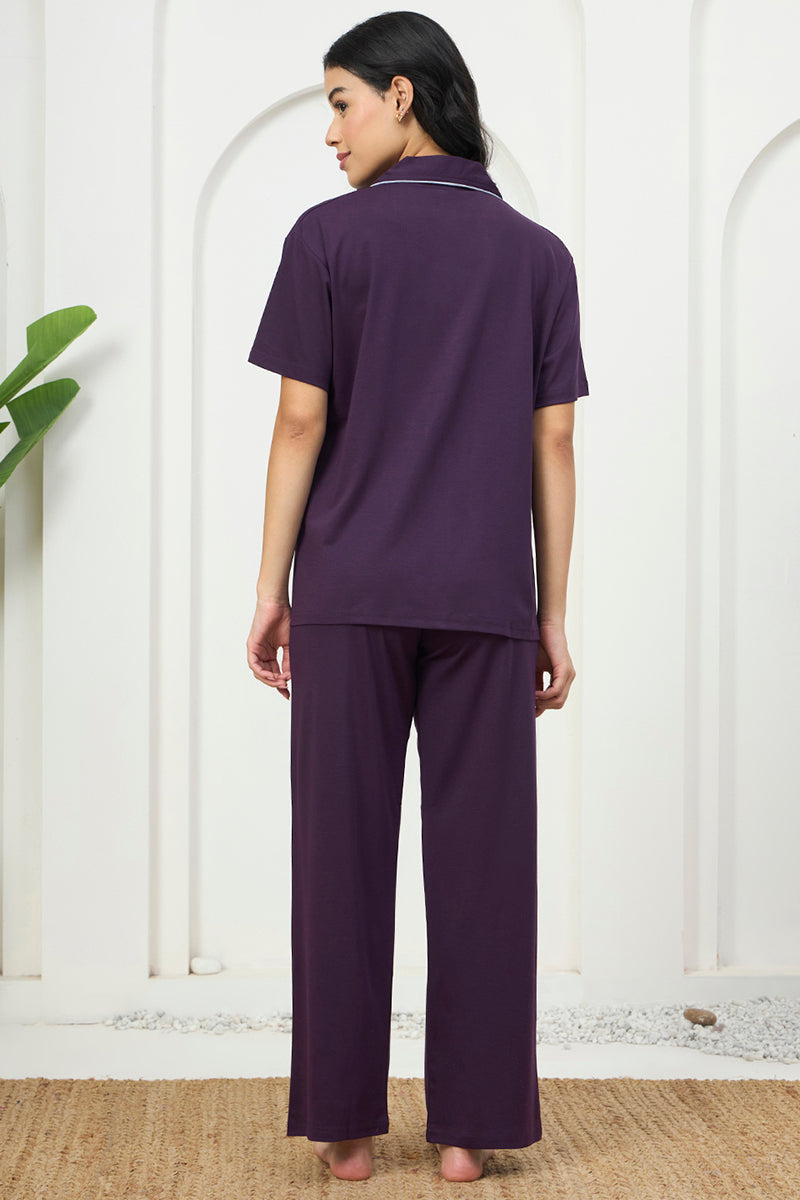 Back view of a woman wearing a purple collared shirt and pants set