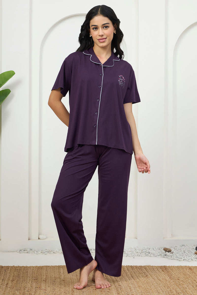 Woman standing in a purple button down shirt and pants pyjama set