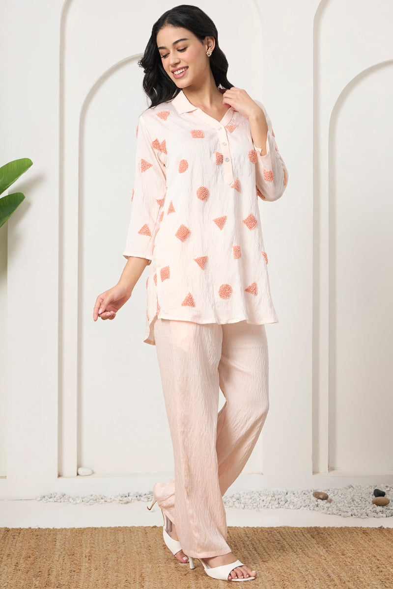 Woman walking outdoors in a peach embroidered tunic co-ord set with textured motifs and matching wide-leg pants