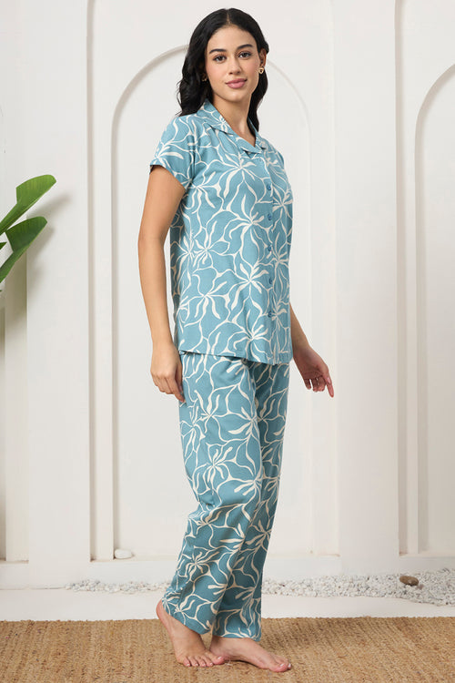 Woman standing in a dusty blue floral print shirt and pants set, side view