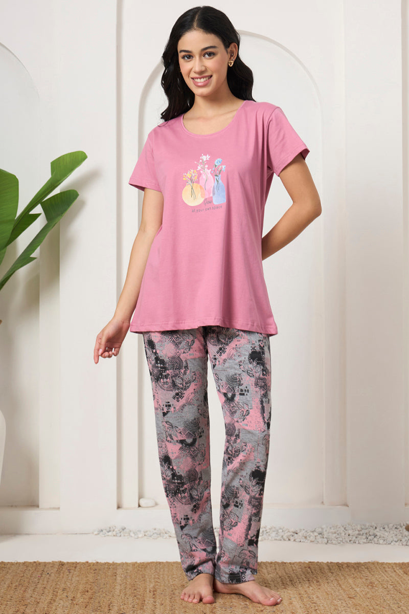 Woman smiling in a pink graphic tee with printed pyjama pants