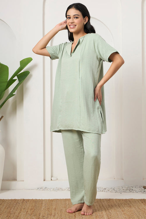 Woman smiling with hand on hip, wearing a sage green tunic and pants set